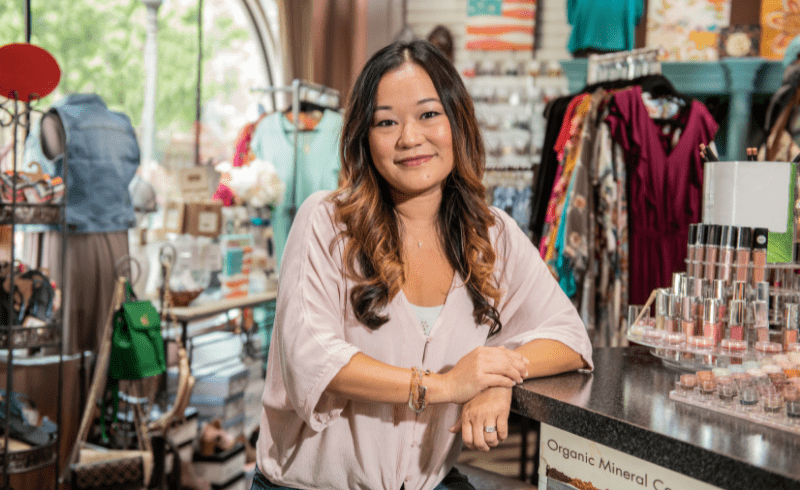 A female small business owner smiles inside her boutique shop