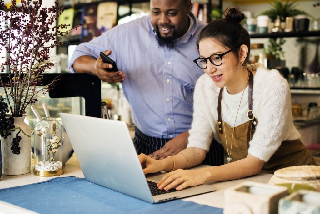 White female business owner and black male business owner using a laptiop