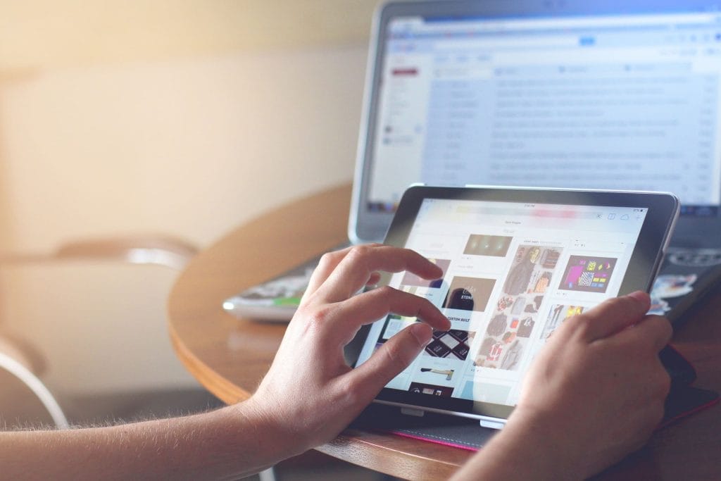 An eCommerce seller looks at her items for sale on a tablet|An eCommerce seller adds items to her online store.