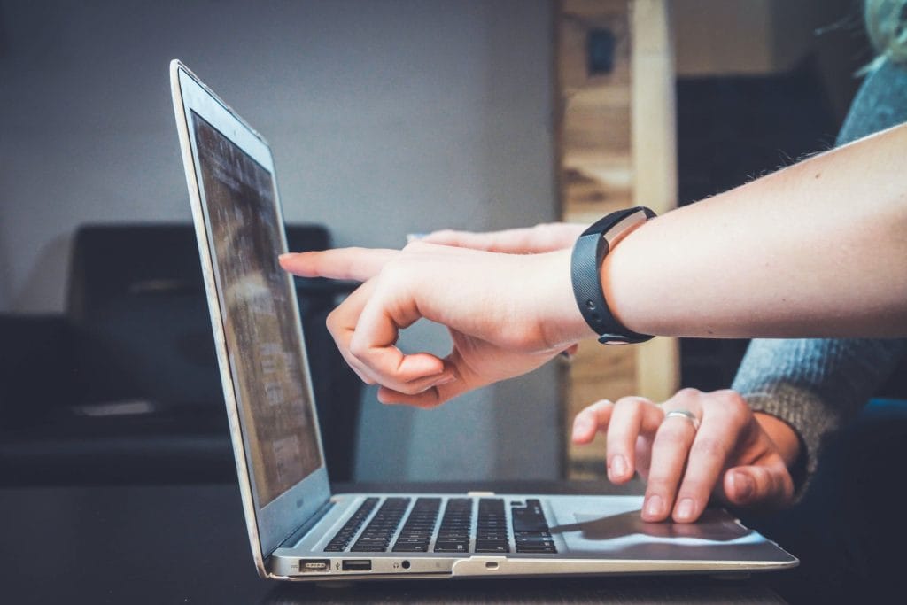 two hands pointing at a computer screen|A man looks at an expense report on his laptop
