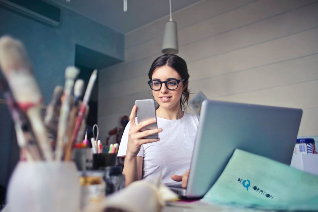 A painter looks at her phone and laptop